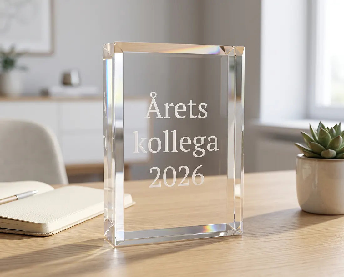 Pris i klar akryl graveret med Årets kollega 2026 på et skrivebord