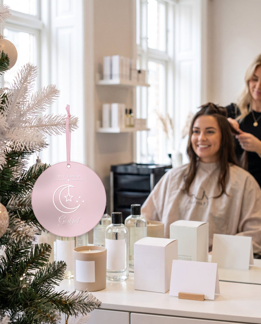 Månesegl: rund julepynt med halvmåne i pink akryl og logo – i brug